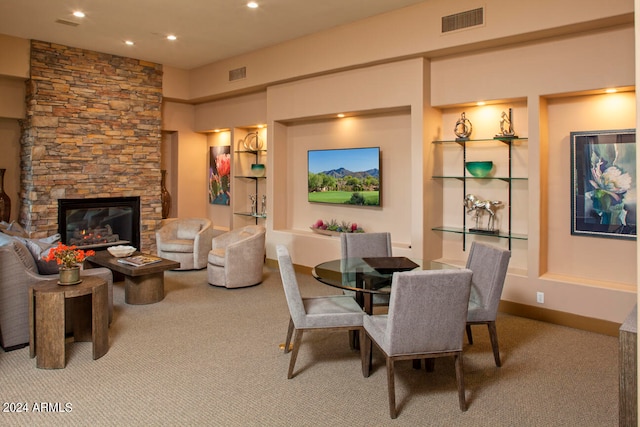 dining room featuring a fireplace and light colored carpet