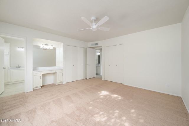 unfurnished bedroom featuring light carpet, ensuite bath, and ceiling fan