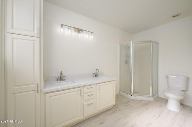 bathroom featuring a shower with door, vanity, wood-type flooring, and toilet