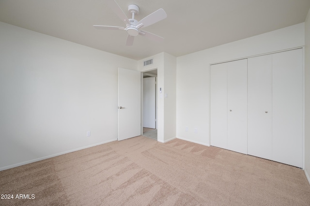 unfurnished bedroom with ceiling fan, a closet, and light colored carpet