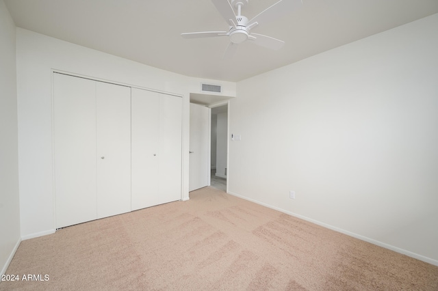 unfurnished bedroom with light colored carpet, a closet, and ceiling fan