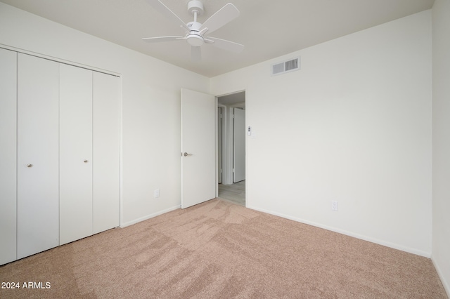 unfurnished bedroom with light carpet, a closet, and ceiling fan