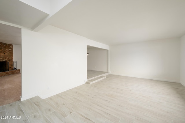 unfurnished room featuring a fireplace and light hardwood / wood-style flooring