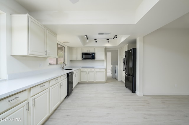 kitchen featuring track lighting, sink, black appliances, independent washer and dryer, and white cabinetry