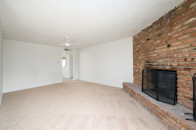 unfurnished living room with a fireplace, light colored carpet, and ceiling fan