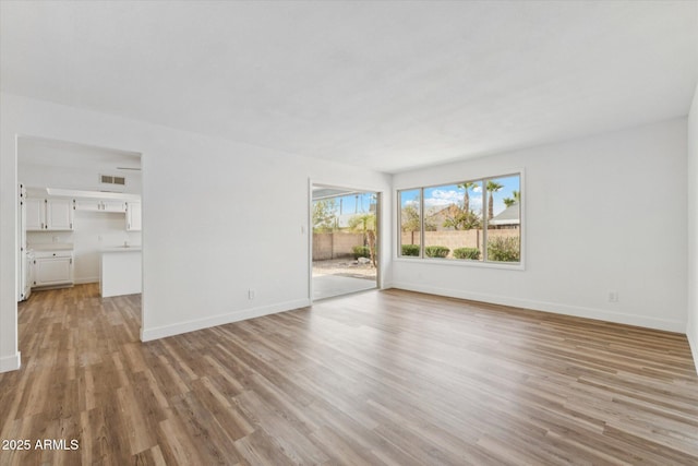 4829 E Apache Cir, Phoenix, AZ 85044 - unfurnished living room featuring light wood-style flooring and baseboards