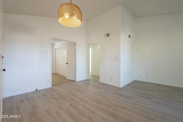 6885 E Cochise Rd Unit 219, Paradise Valley, AZ 85253 - spare room featuring arched walkways, a high ceiling, wood finished floors, and a chandelier