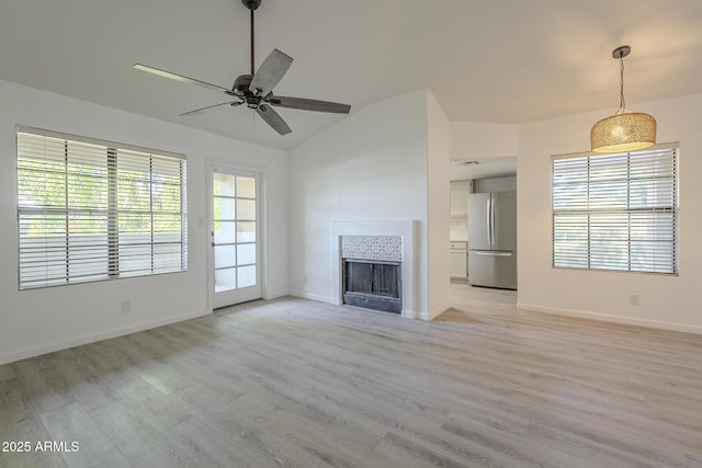 6885 E Cochise Rd Unit 219, Paradise Valley, AZ 85253 - unfurnished living room featuring light wood finished floors, ceiling fan, a tiled fireplace, and vaulted ceiling