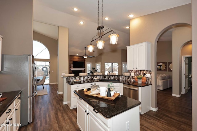 kitchen with kitchen peninsula, appliances with stainless steel finishes, ceiling fan, white cabinets, and hanging light fixtures