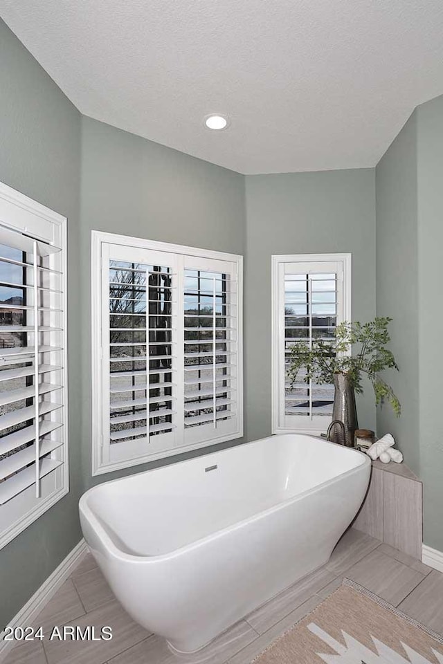 bathroom with tile patterned floors, a tub, and a textured ceiling