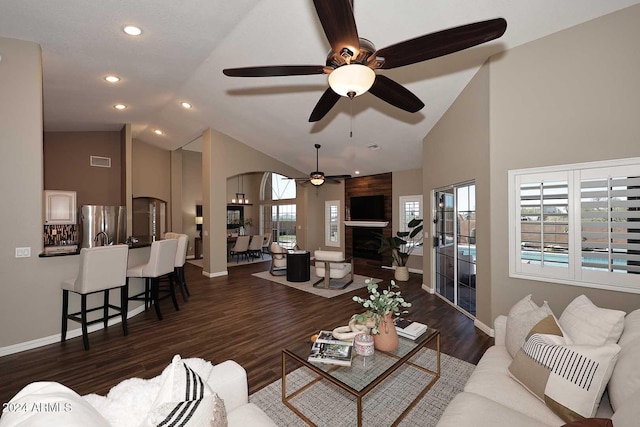 living room featuring dark hardwood / wood-style flooring, ceiling fan, a fireplace, and high vaulted ceiling