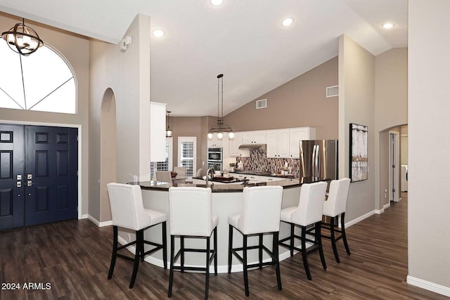 kitchen featuring kitchen peninsula, appliances with stainless steel finishes, decorative backsplash, pendant lighting, and white cabinets