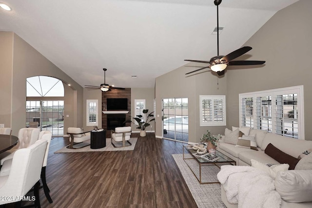 living room with a fireplace, high vaulted ceiling, ceiling fan, and dark wood-type flooring