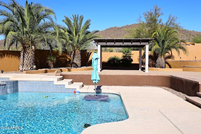 view of swimming pool with pool water feature, a mountain view, a patio area, and a pergola