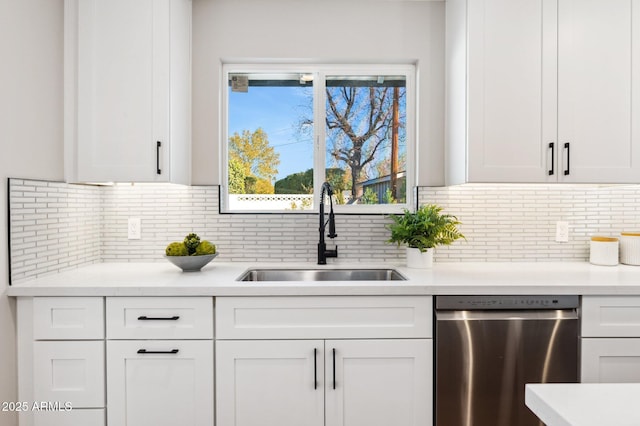 kitchen featuring stainless steel dishwasher, white cabinetry, tasteful backsplash, and sink