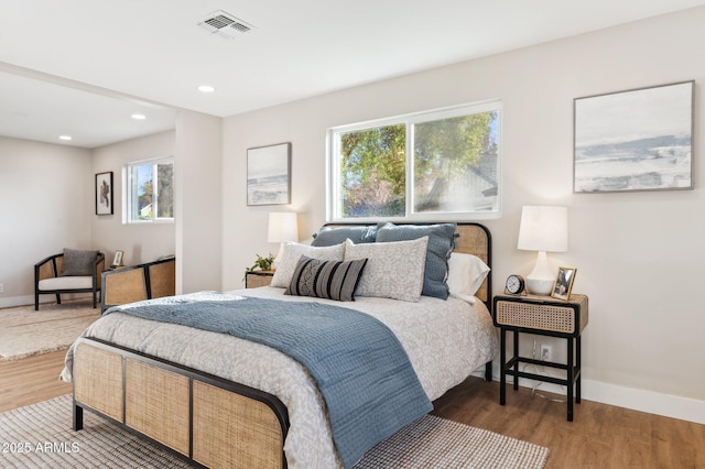 bedroom with multiple windows and dark hardwood / wood-style floors