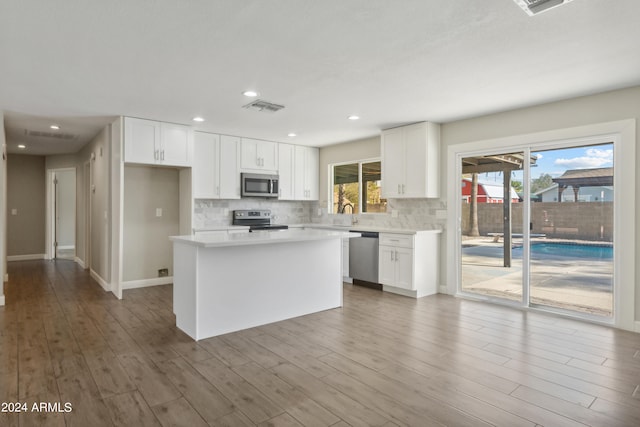 kitchen featuring backsplash, a center island, stainless steel appliances, hardwood / wood-style flooring, and white cabinets