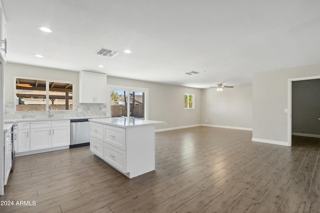 kitchen with dishwasher, white cabinetry, wood-type flooring, ceiling fan, and a kitchen island