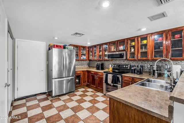 3608 W Harrison St, Chandler, AZ 85226 - kitchen featuring stainless steel appliances, a sink, glass insert cabinets, tasteful backsplash, and a textured ceiling