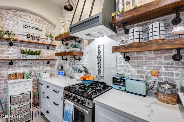 20125 E Via Del Rancho, Queen Creek, AZ 85142 - kitchen with open shelves, exhaust hood, brick wall, white cabinets, and stainless steel range with gas cooktop