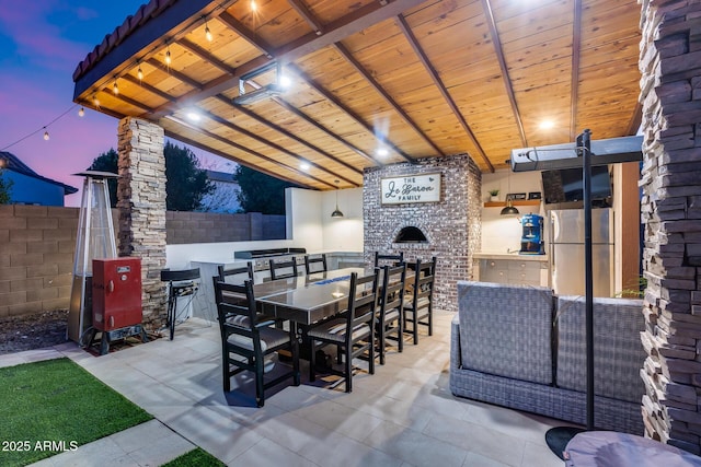 20125 E Via Del Rancho, Queen Creek, AZ 85142 - patio terrace at dusk with outdoor dining area, exterior kitchen, and fence