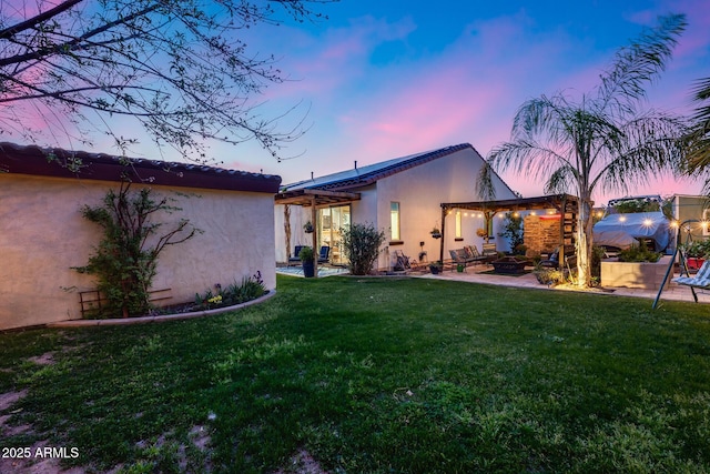 20125 E Via Del Rancho, Queen Creek, AZ 85142 - back of house at dusk with stucco siding, a lawn, a patio, and a pergola