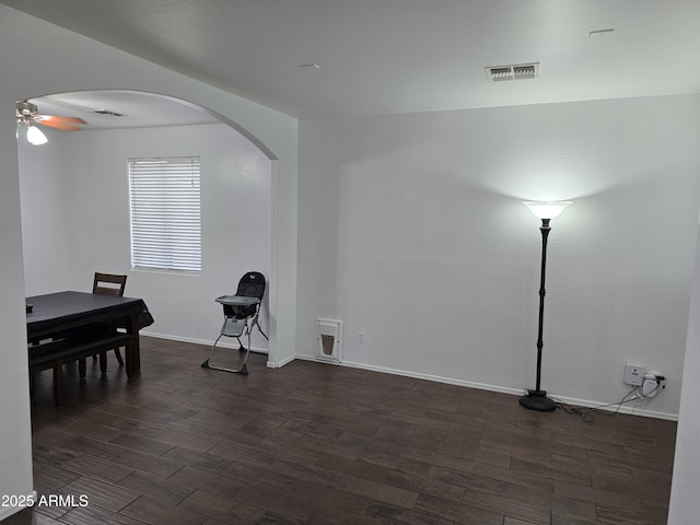 interior space featuring arched walkways, dark wood-type flooring, visible vents, and a ceiling fan