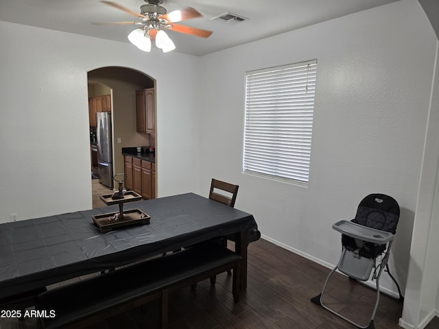 dining area with arched walkways, visible vents, light wood-style floors, ceiling fan, and baseboards