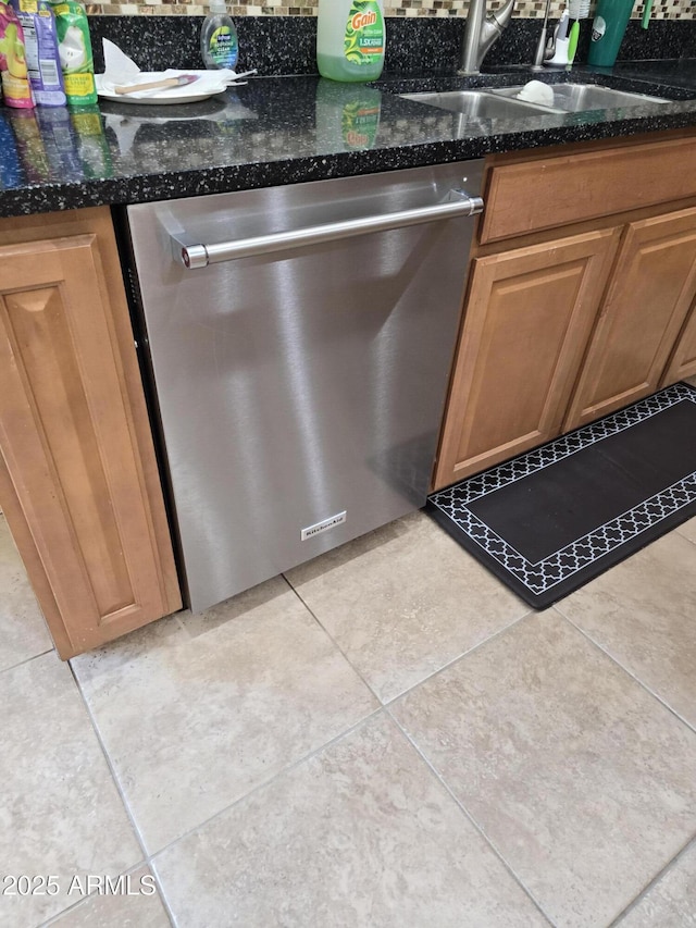 interior details with dark stone countertops, dishwasher, and a sink