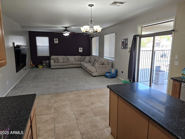 living room with a fireplace, light tile patterned floors, light colored carpet, visible vents, and ceiling fan with notable chandelier