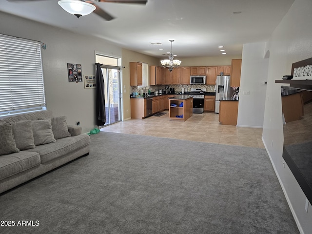 living area with light tile patterned floors, ceiling fan with notable chandelier, baseboards, and light colored carpet