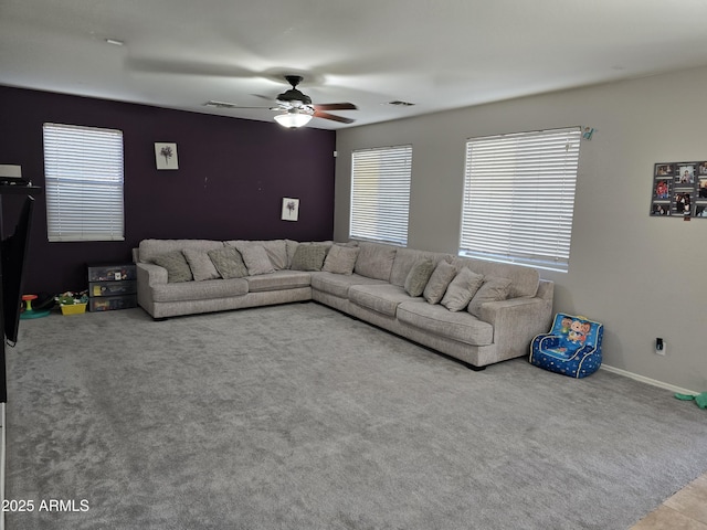 carpeted living room featuring baseboards, visible vents, and a ceiling fan