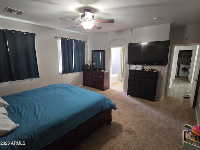 bedroom featuring light carpet, washer / dryer, visible vents, a ceiling fan, and ensuite bath