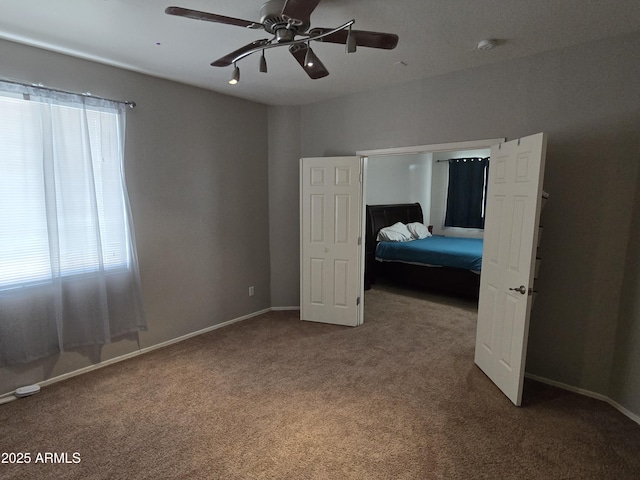 unfurnished bedroom featuring carpet, multiple windows, and baseboards