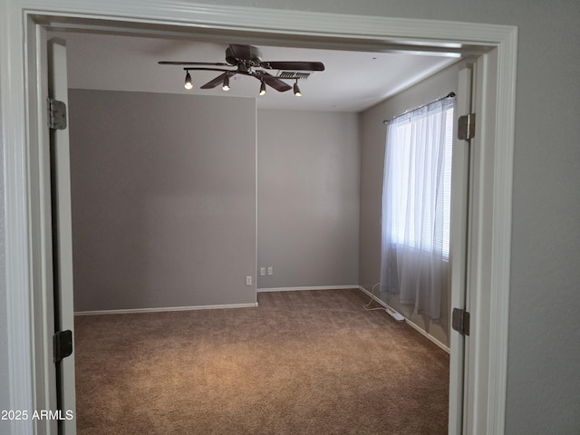 carpeted empty room with ceiling fan and baseboards