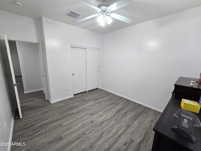 unfurnished bedroom featuring a closet, wood finished floors, visible vents, and baseboards