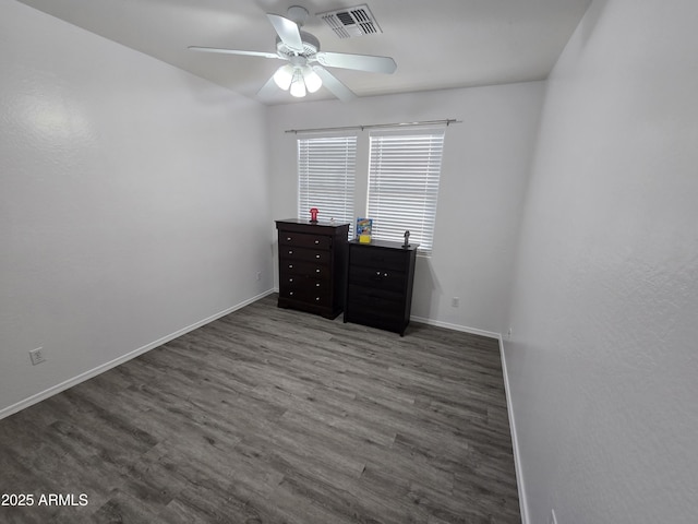 empty room featuring a ceiling fan, visible vents, baseboards, and wood finished floors