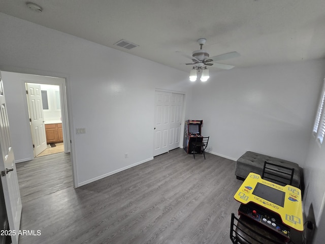 miscellaneous room with a ceiling fan, visible vents, baseboards, and wood finished floors