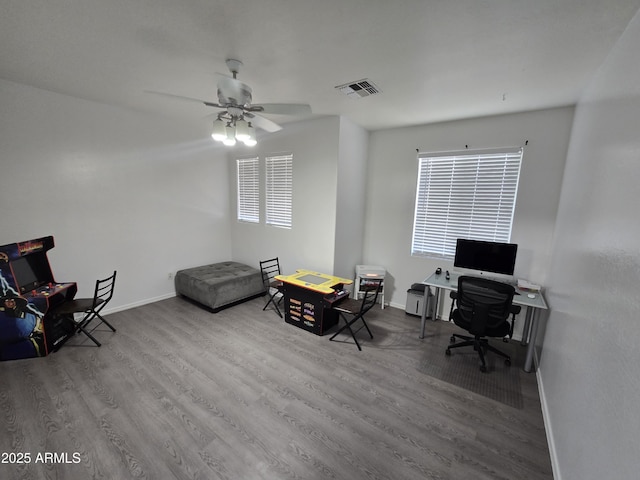 home office with a ceiling fan, visible vents, baseboards, and wood finished floors