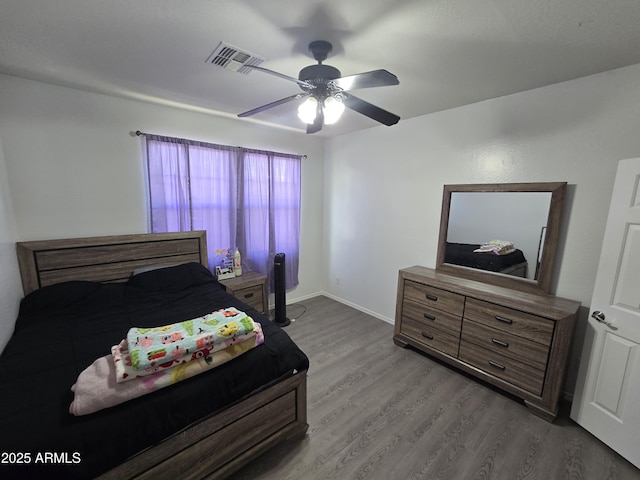 bedroom featuring a ceiling fan, baseboards, visible vents, and wood finished floors