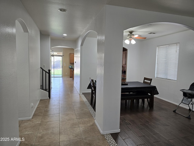 dining room featuring ceiling fan, arched walkways, wood finished floors, visible vents, and baseboards