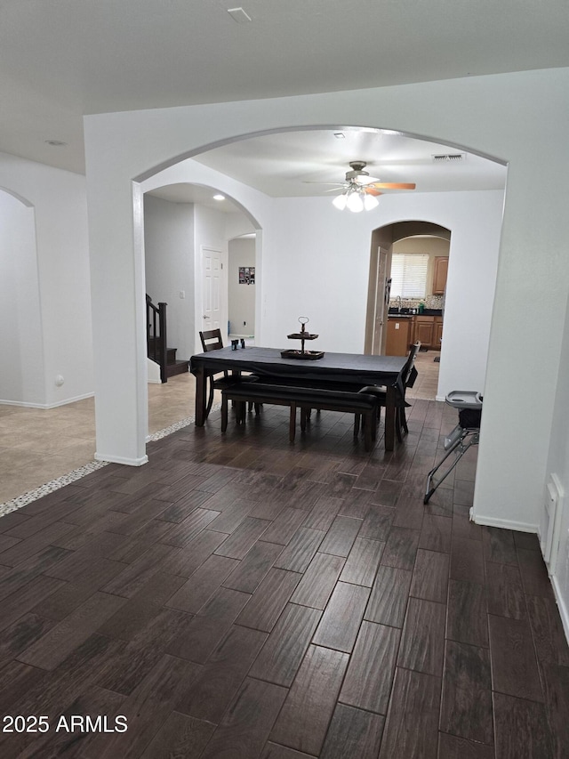 dining area with wood tiled floor, arched walkways, and a ceiling fan