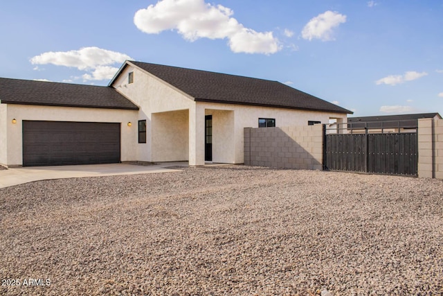 view of front of home with a garage, driveway, fence, and stucco siding