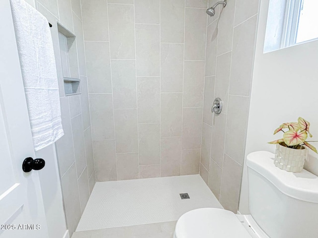 full bath featuring tiled shower and toilet