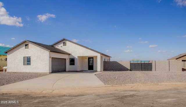 view of front of property featuring a garage, concrete driveway, fence, and stucco siding