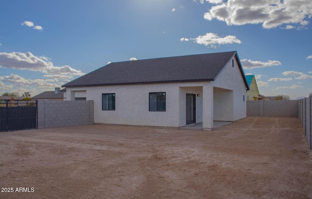 rear view of house featuring a fenced backyard and stucco siding