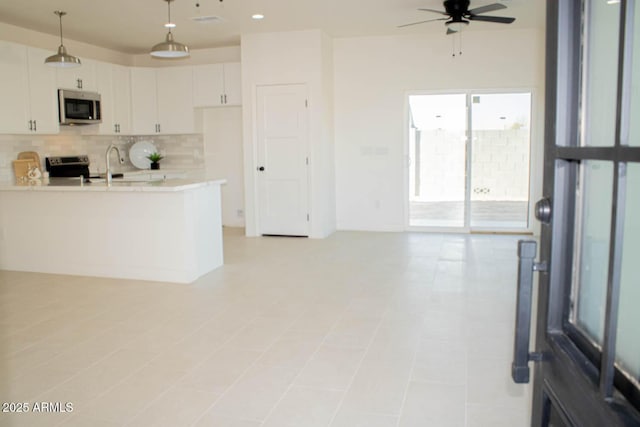 kitchen with tasteful backsplash, light countertops, appliances with stainless steel finishes, white cabinets, and a peninsula