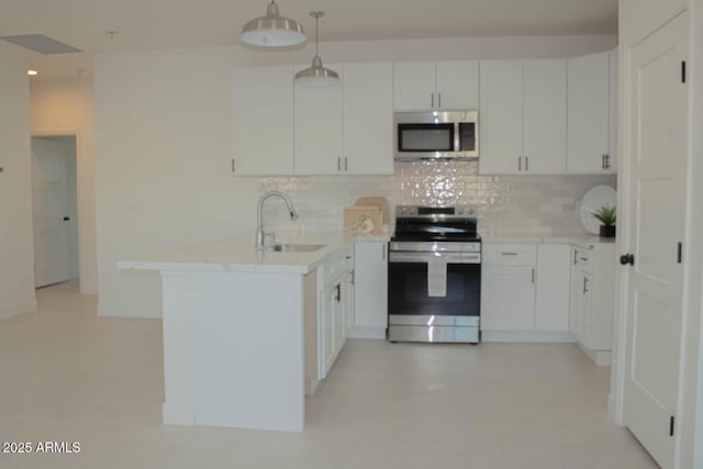 kitchen featuring a peninsula, a sink, white cabinets, appliances with stainless steel finishes, and decorative backsplash