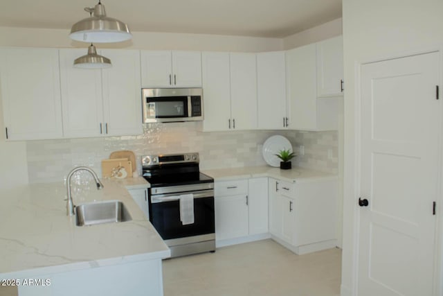 kitchen featuring light stone counters, stainless steel appliances, decorative backsplash, white cabinetry, and a sink