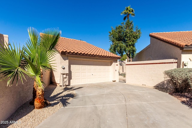 view of front of house featuring a garage, a tiled roof, a gate, fence, and stucco siding